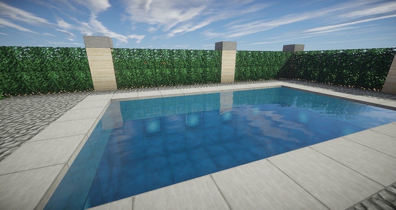 A clean modern swimming pool build in Minecraft surrounded by hedges